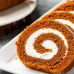 Pumpkin roll with cream cheese swirl on wooden table
