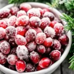 Sugared cranberries in a white bowl coated with sparkling sugar