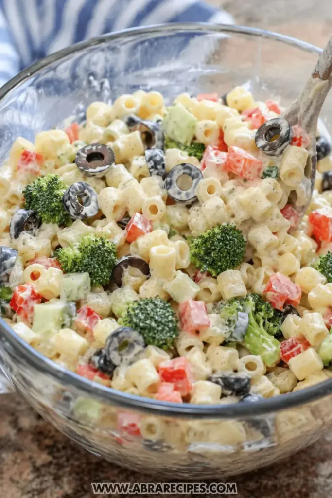 Mixing pasta salad with creamy dressing in bowl