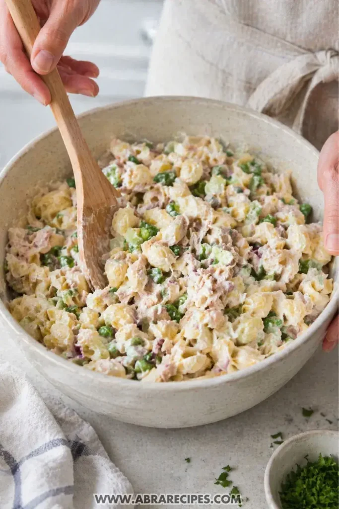 mixing tuna pasta salad with vegetables and creamy dressing
