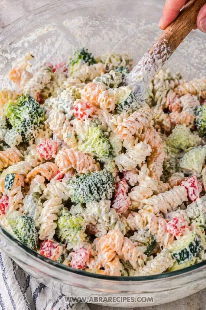 Mixing creamy ranch dressing into pasta salad