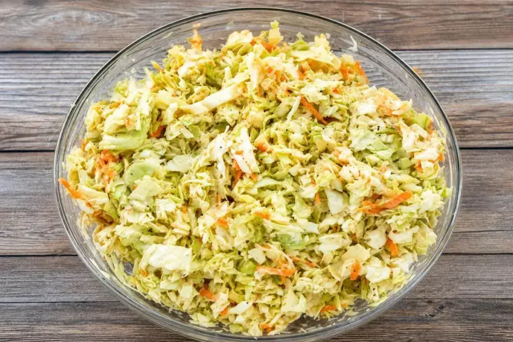 Classic coleslaw recipe in a white bowl with creamy dressing and shredded cabbage