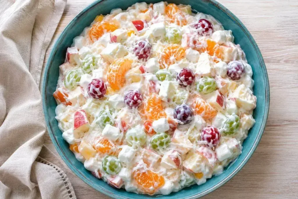 Creamy fruit salad recipe with Greek yogurt, mandarin oranges, grapes, apple, and marshmallows in a teal bowl