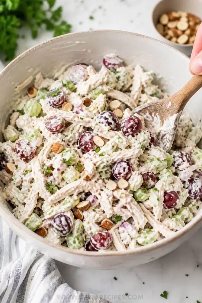Mixing Greek yogurt chicken salad ingredients in a large bowl