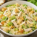 Chicken Caesar Pasta Salad in a white bowl with rotini, romaine, chicken, croutons, and Parmesan