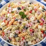 Large bowl of creamy Italian pasta salad with tricolor rotini, salami, mozzarella, black olives, and red bell pepper coated in herby mayo dressing