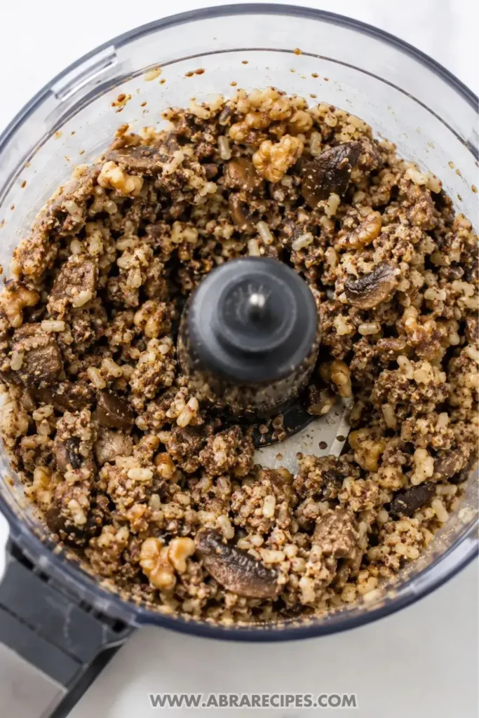 Food processor bowl with mushroom walnut rice mixture for veggie burger patties showing chunky texture
